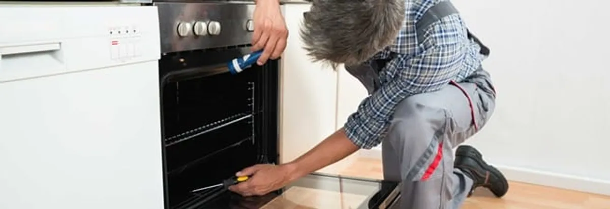 Oven repair technician inspecting and servicing an electric oven in Spokane, WA