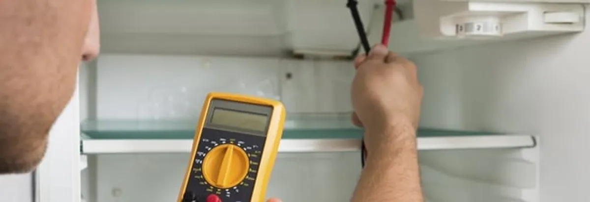 Refrigerator repair technician testing electrical components with a multimeter in Spokane, WA