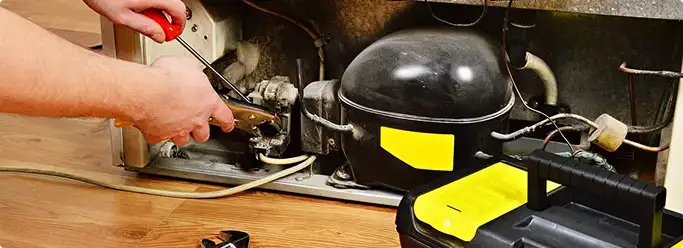 Refrigerator repair technician fixing the compressor and wiring in Spokane, WA
